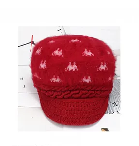Detail of red knitted newsboy hat with fuzzy crown and pink portrait weave patterns