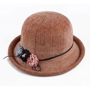 Detail of brown knitted cloche hat featuring rolled brim and three small colorful floral accents