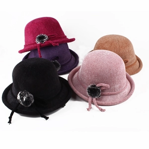 Detail view of stylish knitted cloche hats in various colors with decorative fur pom-poms