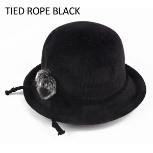 Detailed texture of black knit winter bucket hat with pom-pom and ribbon bow accent