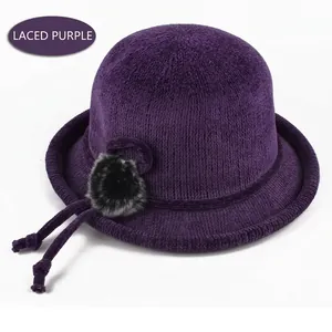 Detail of purple knitted bucket hat featuring a plush fur ball and elegant lace-up bow