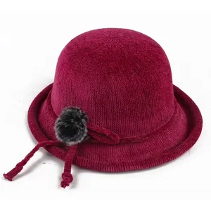 Close-up of wine red knitted bucket hat with vertical texture and grey pompom detail