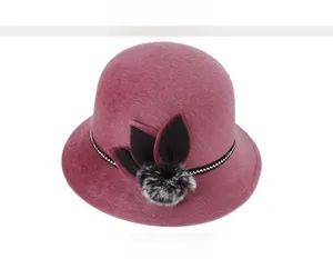 Detail of burgundy faux mink fur hat with stylish weave band and fur ball accent