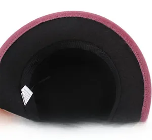 Close-up of pink and black felt hat interior with sweatband and care label