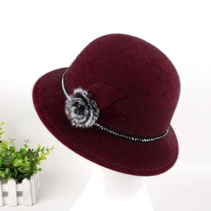 Close-up of wine red faux mink fur hat featuring a plush pom-pom and elegant ribbon trim