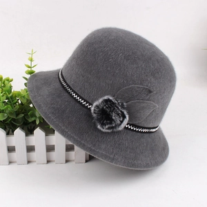 Detail of dark grey winter cloche hat with textured wave band and plush faux fur pom-poms