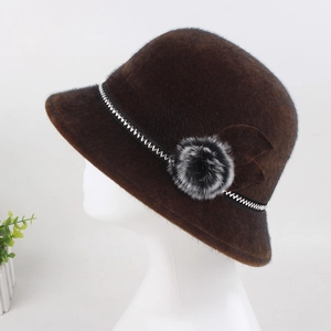 Detail of dark brown faux mink fur hat with decorative plush floral pom-poms and ribbon