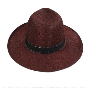 Detail of burgundy wide-brim straw hat featuring a black ribbon with contrast stitching