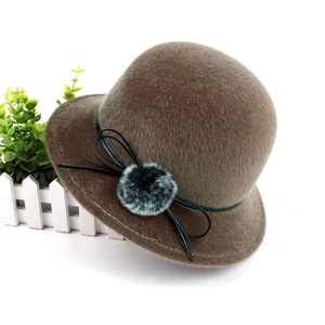 Close-up of brown faux mink fur winter hat featuring a stylish bow and soft pompom detail