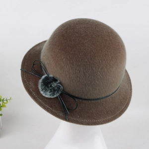 Close-up of brown cloche hat with black leather bow and faux fur pompom detail