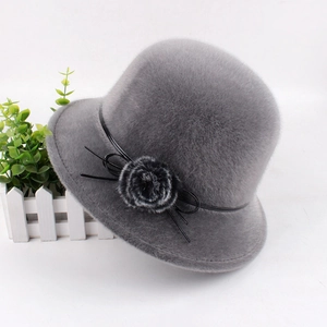 Detailed close-up of grey faux fur hat with black ribbon and floral plush ball accessory