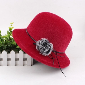 Detail of red faux mink fur hat with black decorative band and side flower accent