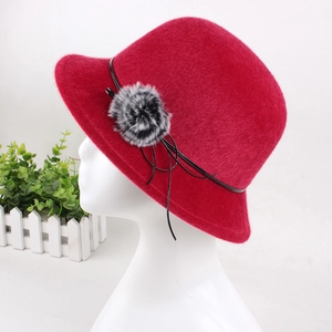 Detailed close-up of a red faux mink fur cloche hat with a black leather cord and pompom