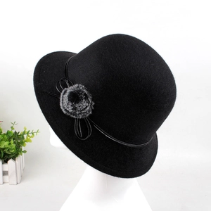 Detail of cloche hat with faux fur pompom, lacquer band and elegant bow decoration