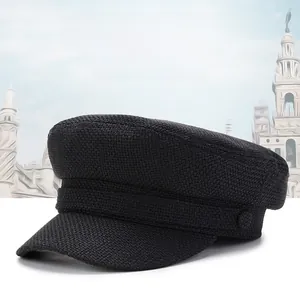 Détail d'un béret noir en maille texturée avec bande décorative et boutons sur le côté