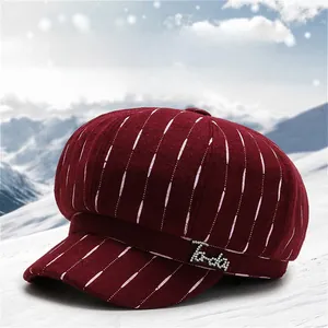 Detail of burgundy striped octagonal newsboy hat with rhinestone letters on snow background