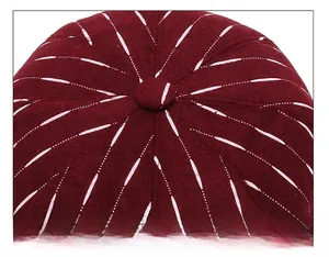 Detail of burgundy wool octagonal hat with central button and white radial stitching