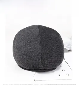 Detail view of dark grey tweed flat cap with thick wool blend texture for winter