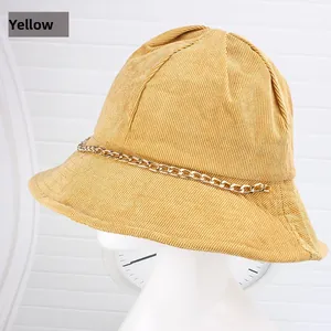 Dettaglio ravvicinato di un cappello a secchiello in velluto giallo con catena dorata