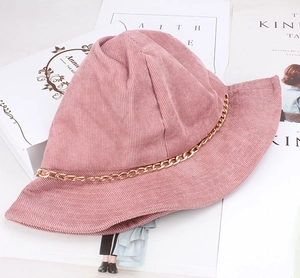 Dettaglio di cappello pescatore in velluto a coste rosa con catena dorata