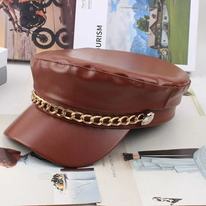 Brown leather newsboy cap with bold gold chain detail and polished silver buttons