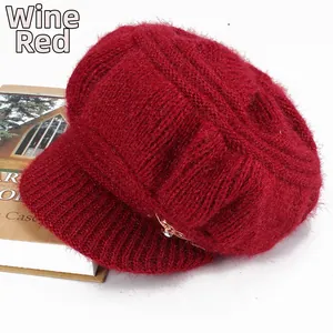 Detail of burgundy knitted winter hat with soft mohair texture and gold crown emblem
