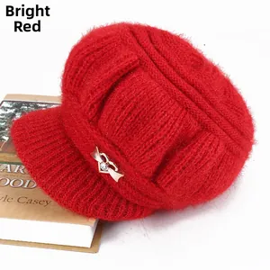 Detail of red knit baker boy hat with golden metal bow and rhinestone decoration