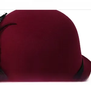 Detail of wine red wool felt bowler hat with black feather and lace embellishment