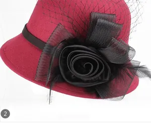 Detail of burgundy wool fedora with large black flower, feathers and mesh veil