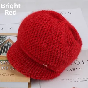 Detail of red mohair knit baker boy hat with golden metal plate and fuzzy texture