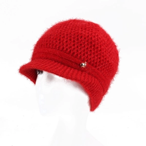 Close-up of red knit hat texture with small brim and golden apple metal accessory