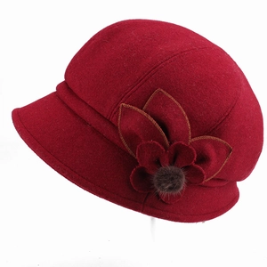 Detail view of burgundy cloche hat with fabric flower and fur pompom accent