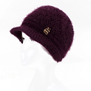 Detail of dark purple knitted cloche hat featuring a golden apple-shaped metal emblem