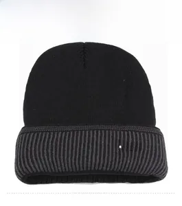 Detail view of black knit beanie featuring grey ribbed cuff and metallic JEANS badge