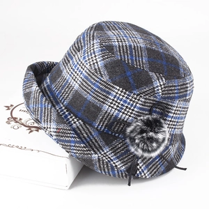 Detailansicht der Winter-Topfhut mit blauem Karomuster und flauschigem Pelzball-Dekor