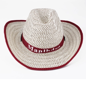 Detail of woven straw cowboy hat featuring red fabric trim and branded ribbon band