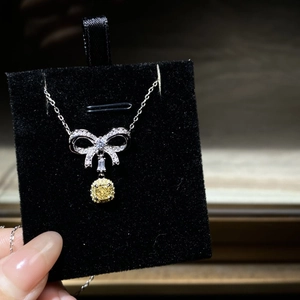 Dettaglio macro della collana a fiocco in argento S925 con diamante rosa e gemma gialla