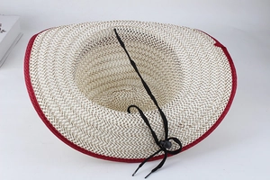 Detail showing inner structure of beige straw sun hat with red trim and chin strap