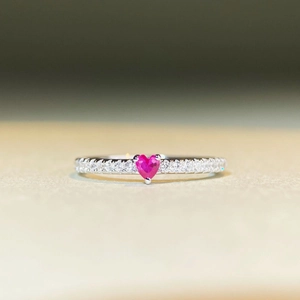 Dettaglio dell'anello d'argento con gemma a cuore magenta e pavé di diamanti scintillanti