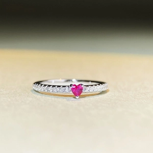 Vista macro di un anello in argento 925 con rubino rosso a cuore e piccoli diamanti