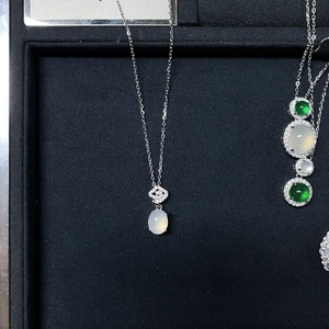 Detailed macro of a silver necklace featuring an oval white gemstone and pave-set bail