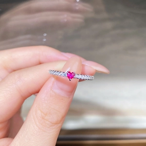 Dettaglio macro dell'anello con rubino a cuore e diamanti laterali in argento