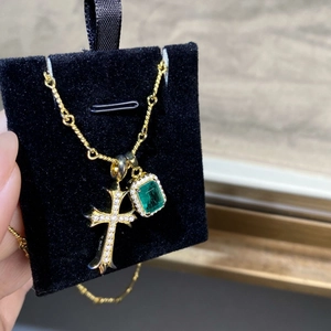 Macro shot of S925 silver cross with emerald pendant on gold twisted chain