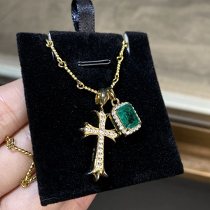 Close-up of S925 sterling silver gold cross and emerald cut green stone pendants