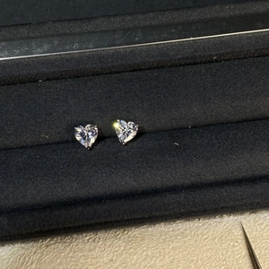 Detailed close-up of 1ct heart-cut moissanite stud earrings on a black velvet cushion