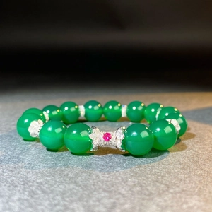 Détail macro du bracelet en perles d'agate verte avec un charm papillon en argent