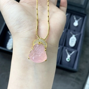 Close-up of pink agate Buddha pendant with gold bamboo chain on a jewelry box