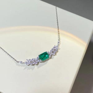 Detail of emerald cut green stone necklace with leaf shaped side stones in silver