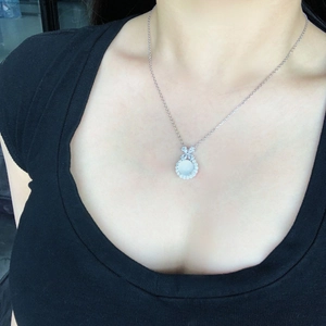 Close-up of S925 sterling silver bow pendant with white chalcedony worn by model