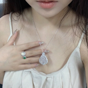 Detailed view of Buddha pendant necklace and dual-stone ring worn by model